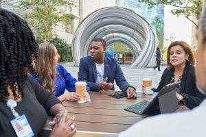 Team members share coffee and conversation at outdoor table at Dallas HQ