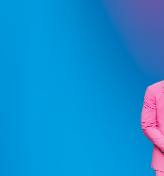 Jamaal in pink suit in front of blue gradient backdrop