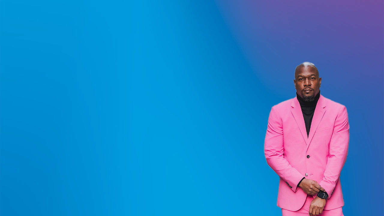 Jamaal in pink suit in front of blue gradient backdrop