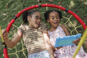 Two sisters use the AT&T amiGO Tab while relaxing in their backyard. (Marketing photo - includes hired actors representing AT&T customers.)