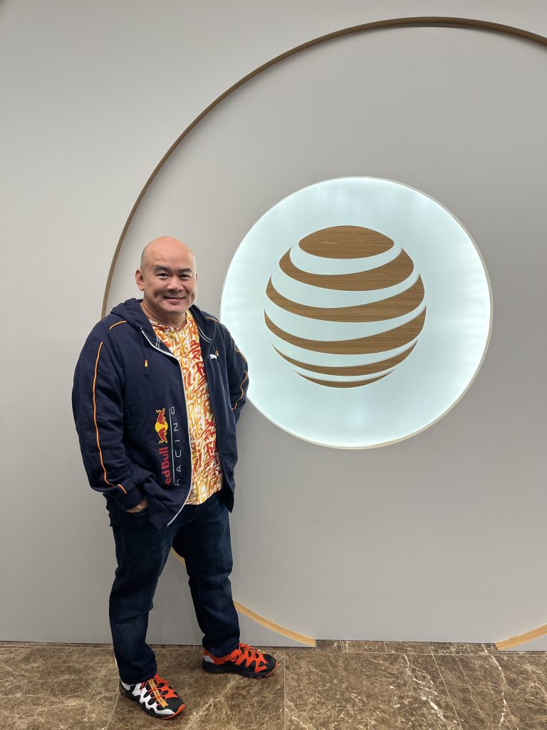 man in colorful sneakers, jeans, bright patterned shirt, and graphic jacket