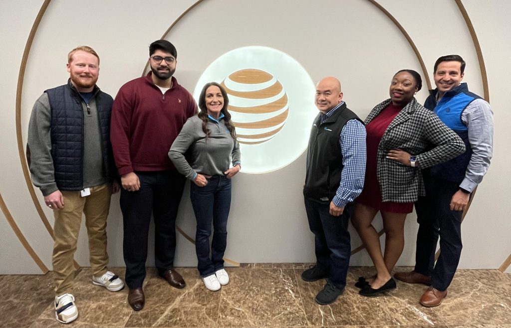 Team members pose in front of AT&T logo showing off appropriate outfits