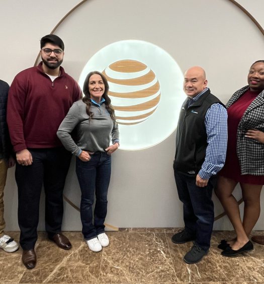 Team members pose in front of AT&T logo showing off appropriate outfits