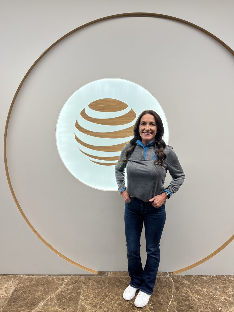 Woman in AT&T quarter zip, jeans, and white shoes