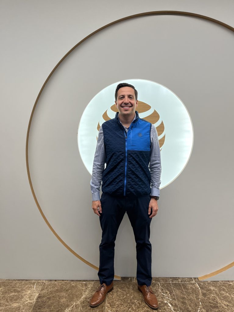 Man in AT&T branded vest, blue button down, slacks, and dress shoes