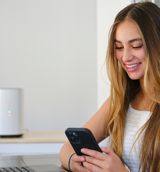 Woman checks her phone while working at a laptop